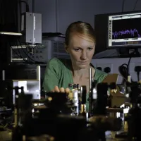 Professor Anna Peacock at work surrounded by equipment in the photonics lab