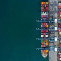 Top-down view of colourful shipping containers at a seaport with clear water